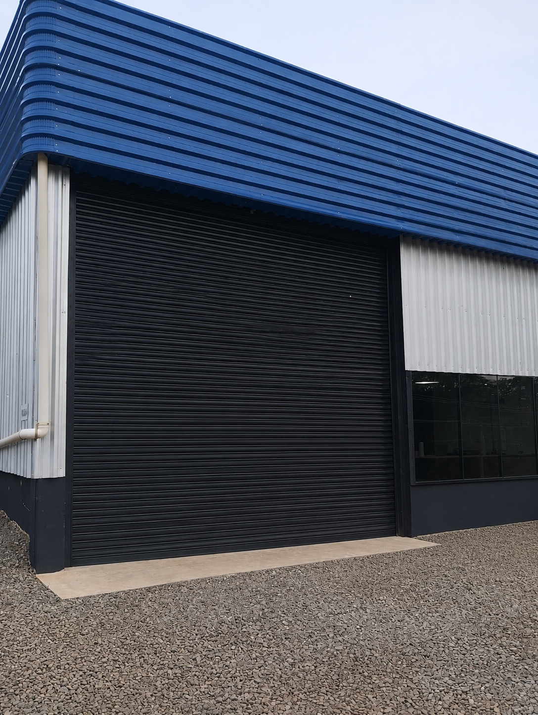 Sede e oficina Schreiner — fachada industrial com portão metálico preto